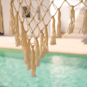 uma rede branca com tassels ao lado de uma piscina