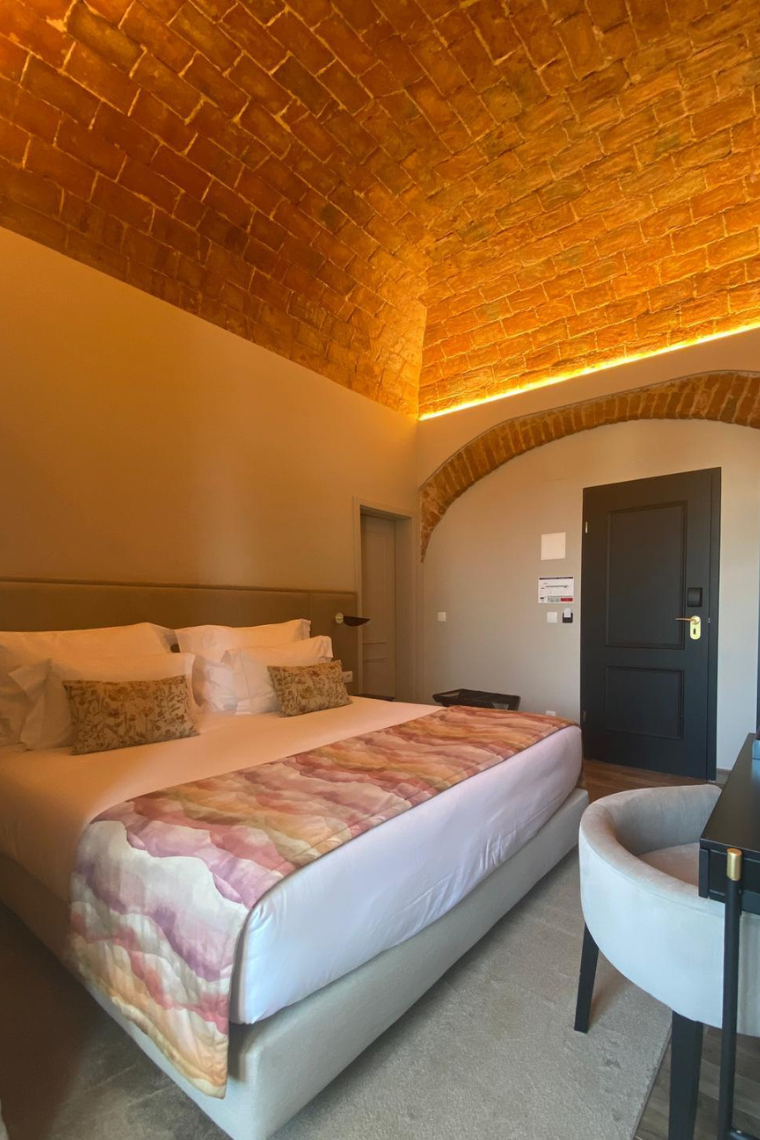 a hotel room with a large bed and a brick ceiling