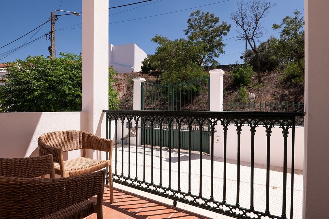 a balcony with wicker chairs and a green gate