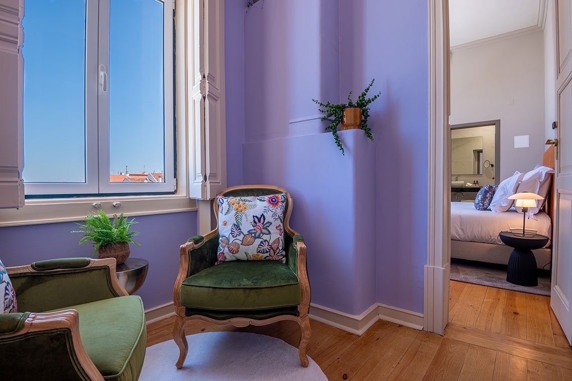 a chair with a floral pillow sits in a room with purple walls
