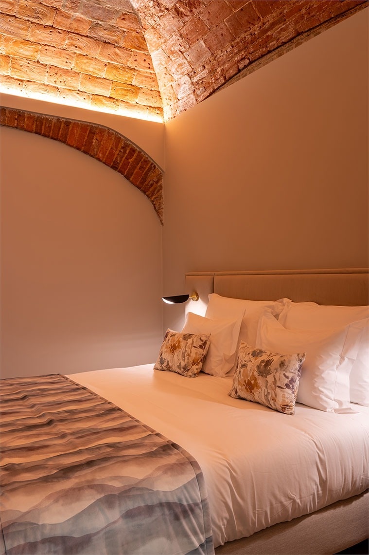 um quarto com cama e travesseiros e uma parede de tijolos