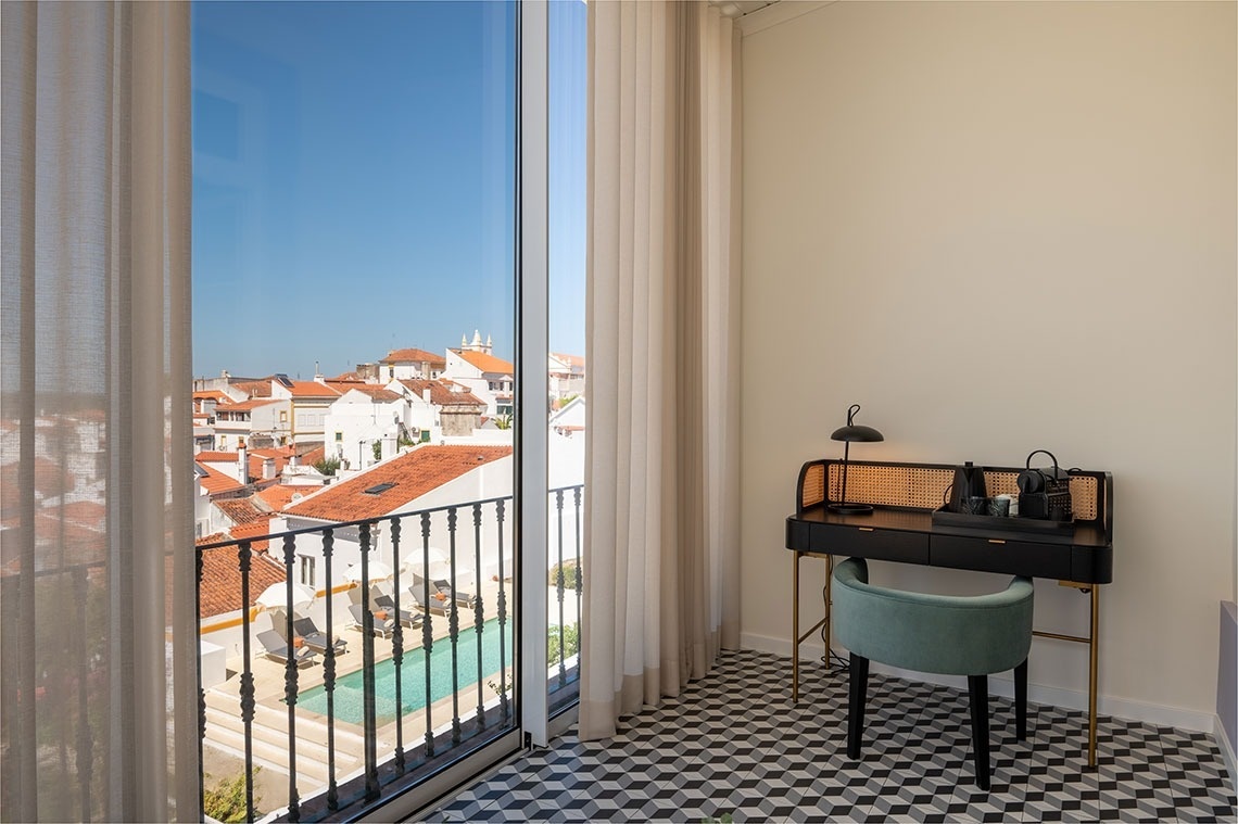 a room with a desk and chair with a view of a pool