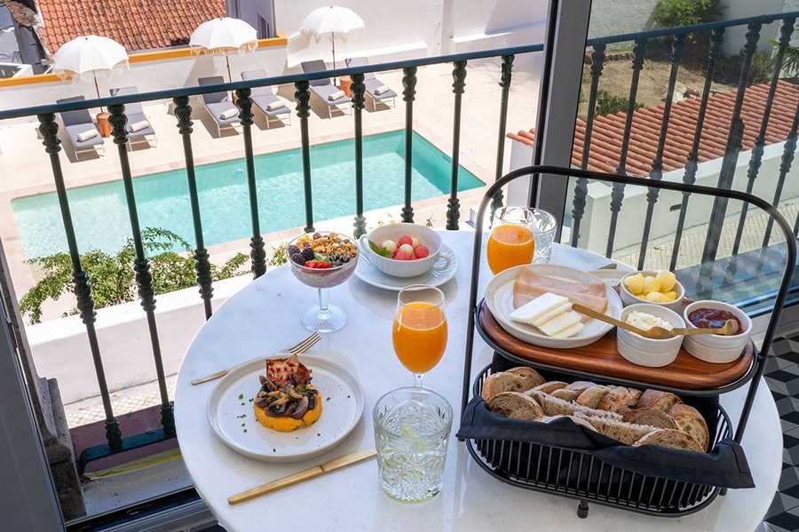 a table with food and drinks on it with a pool in the background