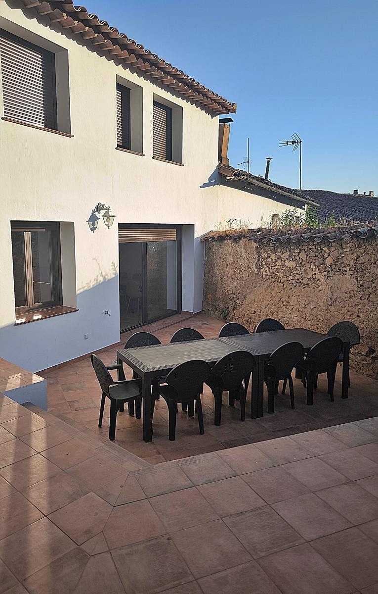 una mesa y sillas en un patio frente a una casa