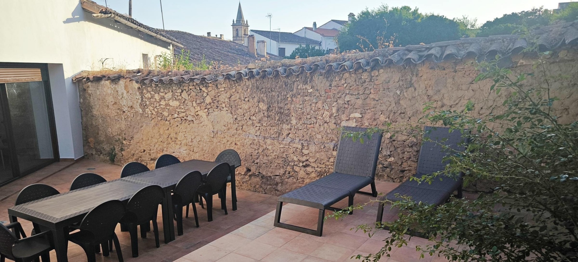 una mesa y sillas en un patio con una pared de ladrillo en el fondo