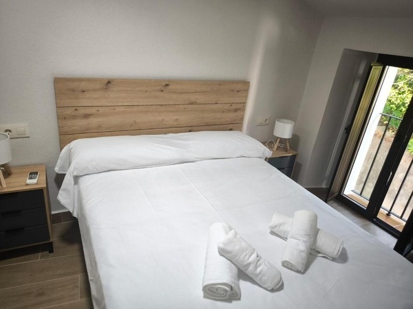 una cama con sábanas blancas y una cabecera de madera