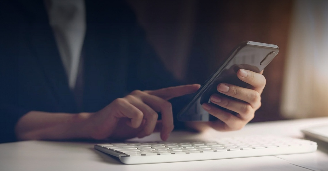 una persona está usando un teléfono inteligente junto a un teclado