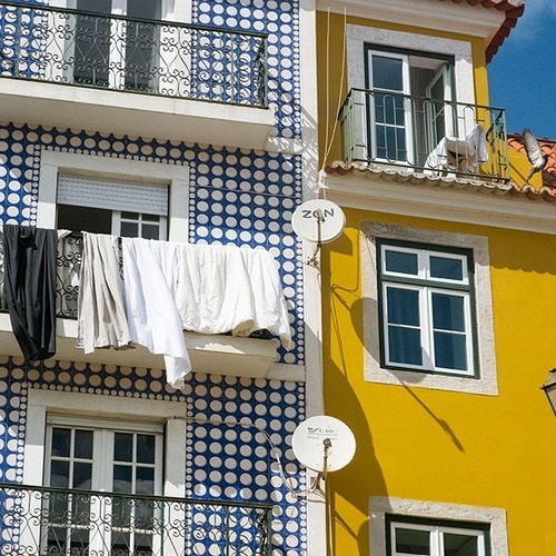 um pássaro voa sobre um prédio amarelo e azul