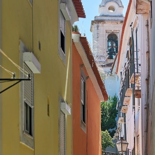 a narrow alleyway with a church in the background