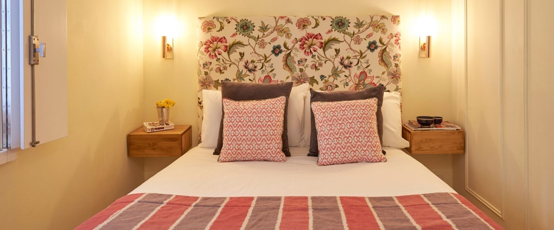 a bed with a floral headboard and pillows on it