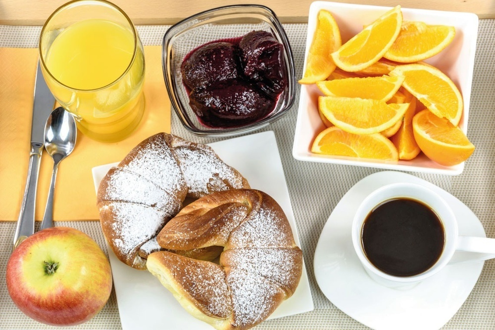 uma bandeja de café da manhã com um croissant coberto com açúcar em pó