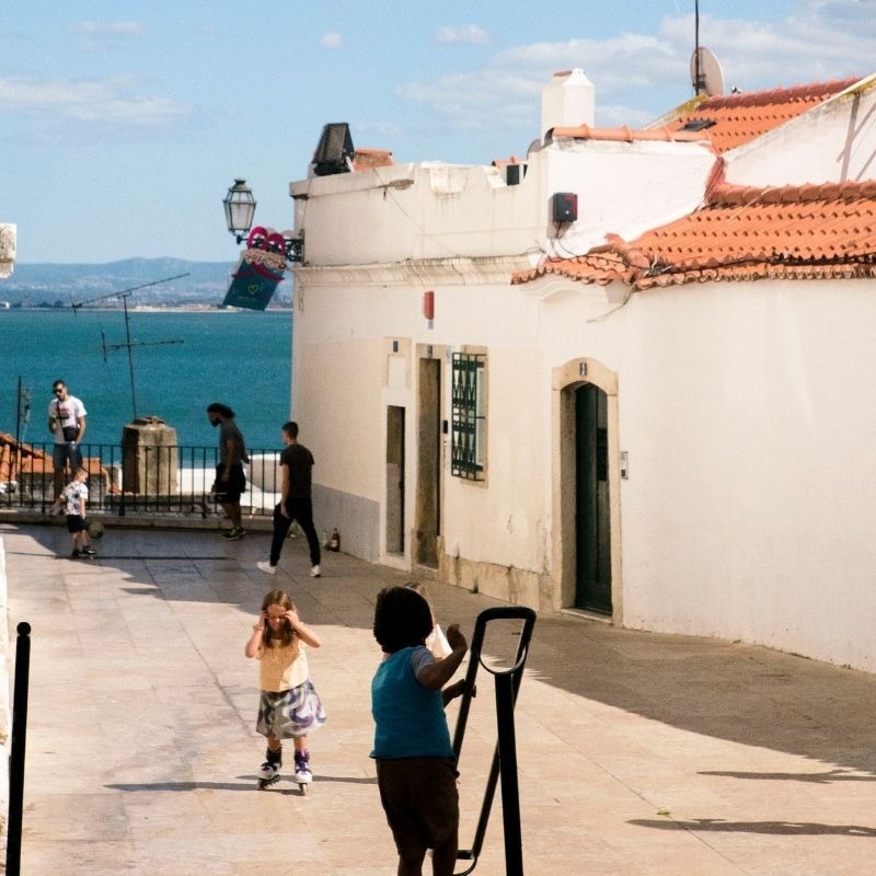 um sinal rosa e azul com um coração e a palavra alfama ao lado de um prédio