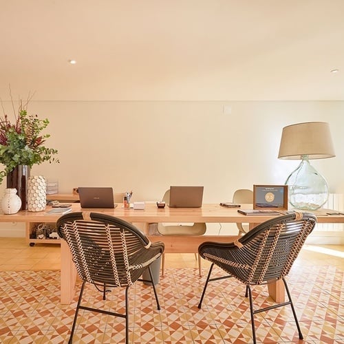 a desk with two chairs and two laptops on it