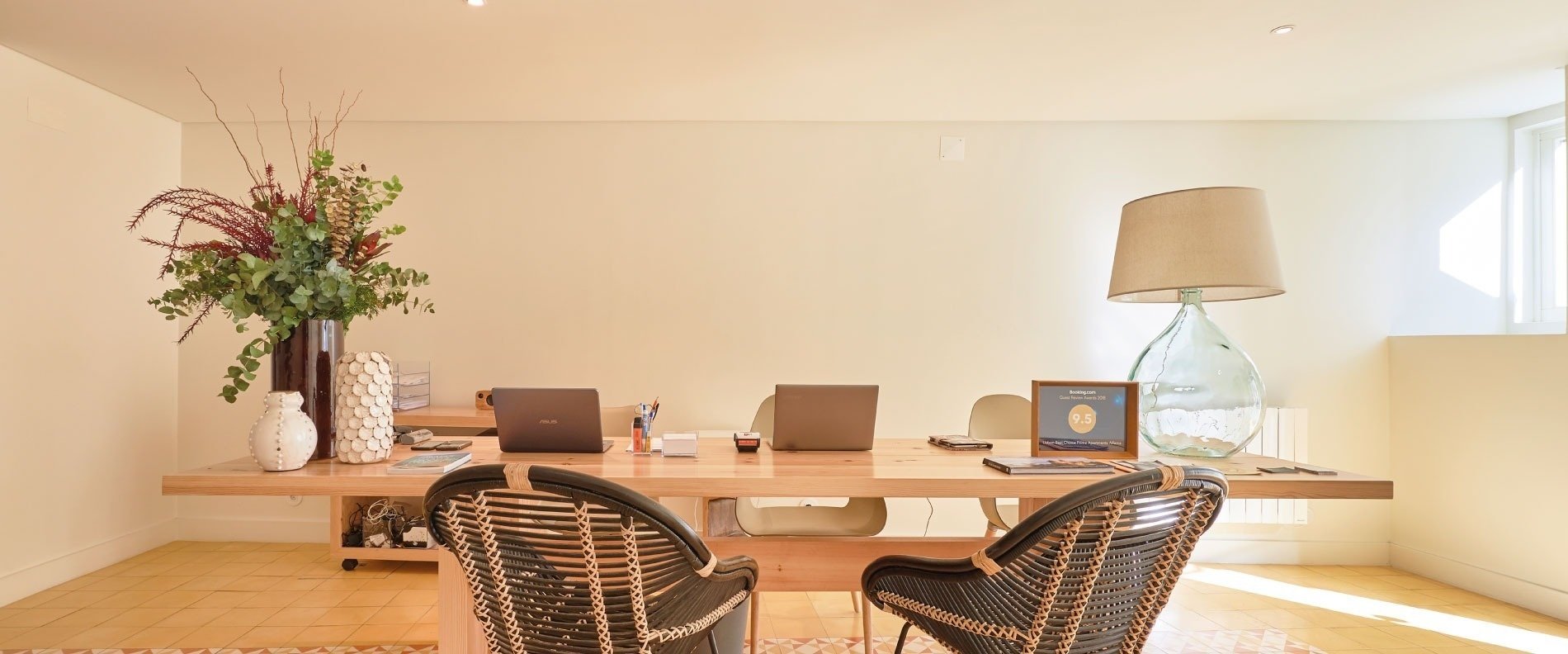 two chairs sit at a desk with a laptop and a vase of flowers