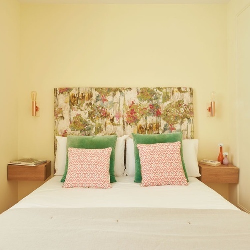 a bed with a floral headboard and pillows on it