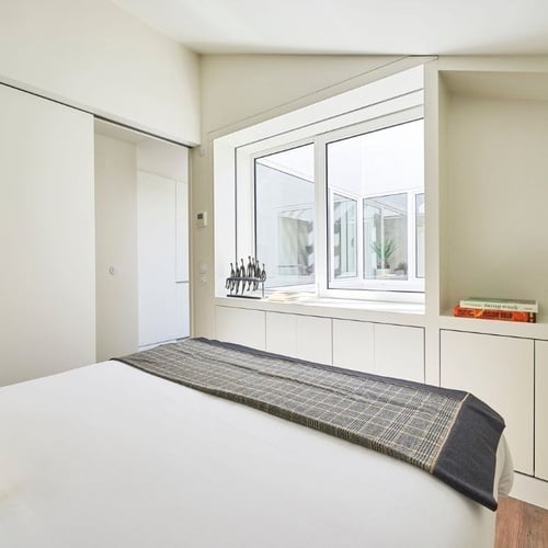 a bedroom with a bed and a window with a book on the shelf