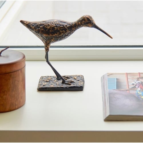 a statue of a bird sits on a window sill next to a book