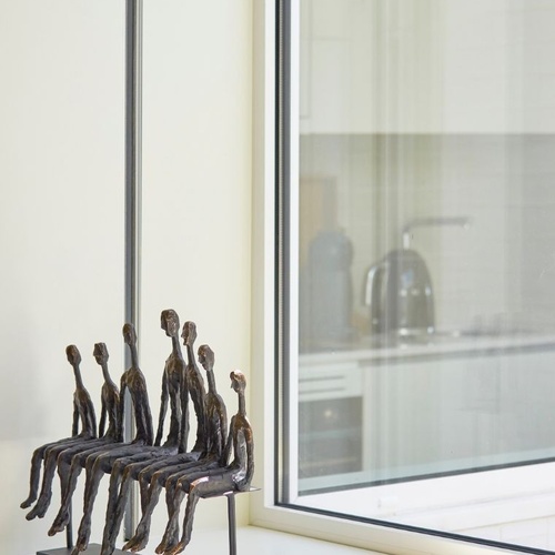 a statue of people sits on a window sill next to a stack of books