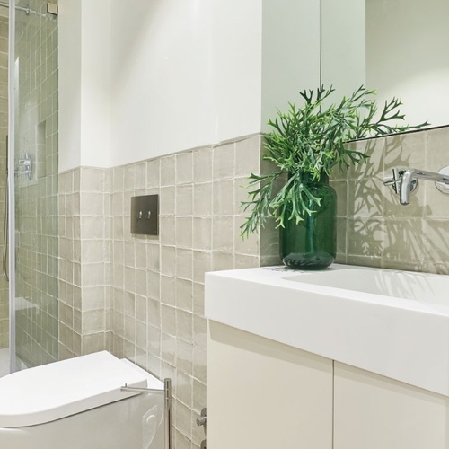 a bathroom with a sink and a shower with green tiles