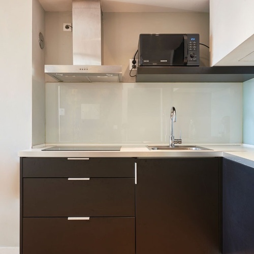 a small kitchen with black cabinets and a samsung microwave