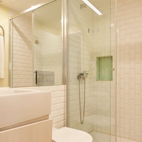 a bathroom with white tiles and a walk in shower