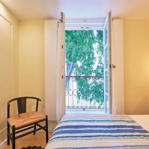 a bedroom with a bed a chair and a balcony