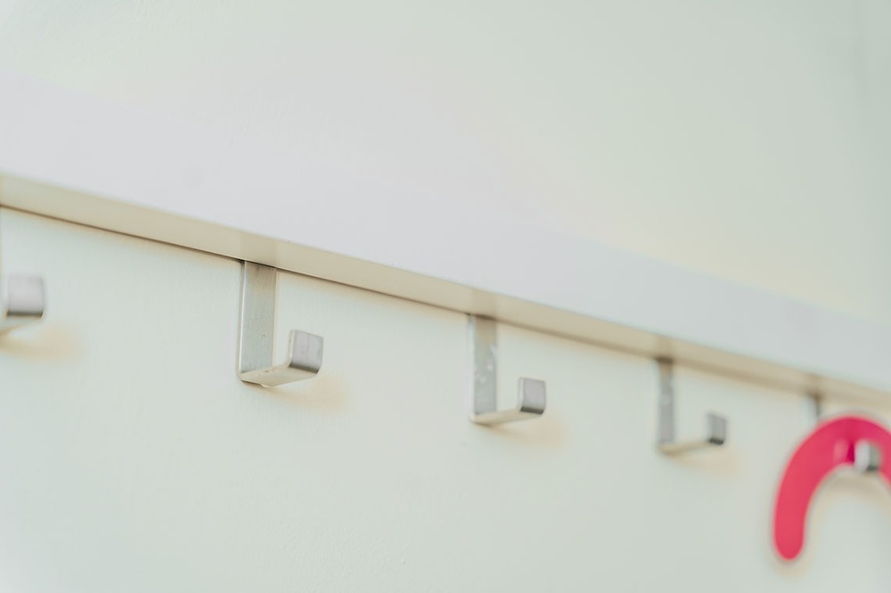 uma parede branca com ganchos de aço inoxidável