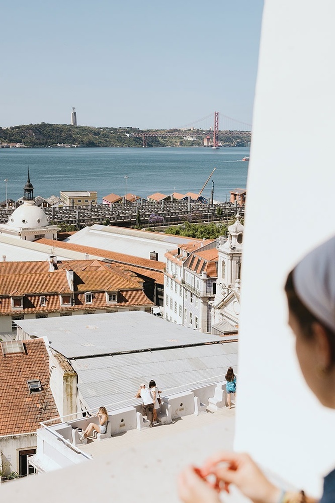 pessoas sentadas no telhado de um prédio com vista para o oceano