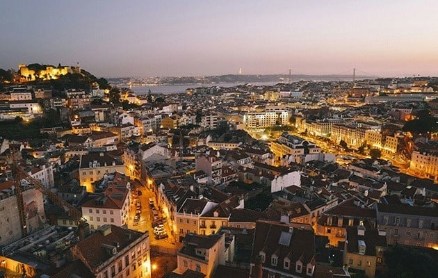 an aerial view of a city at night with a bridge in the distance