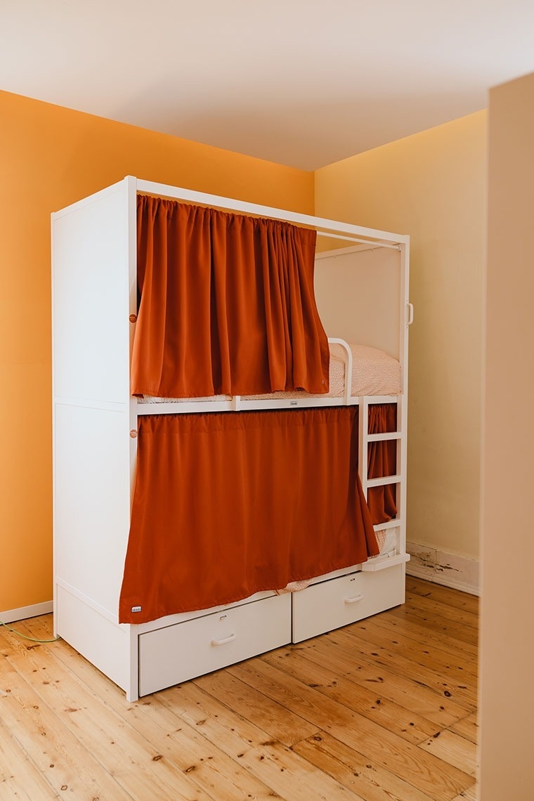 a bunk bed in a room with orange curtains