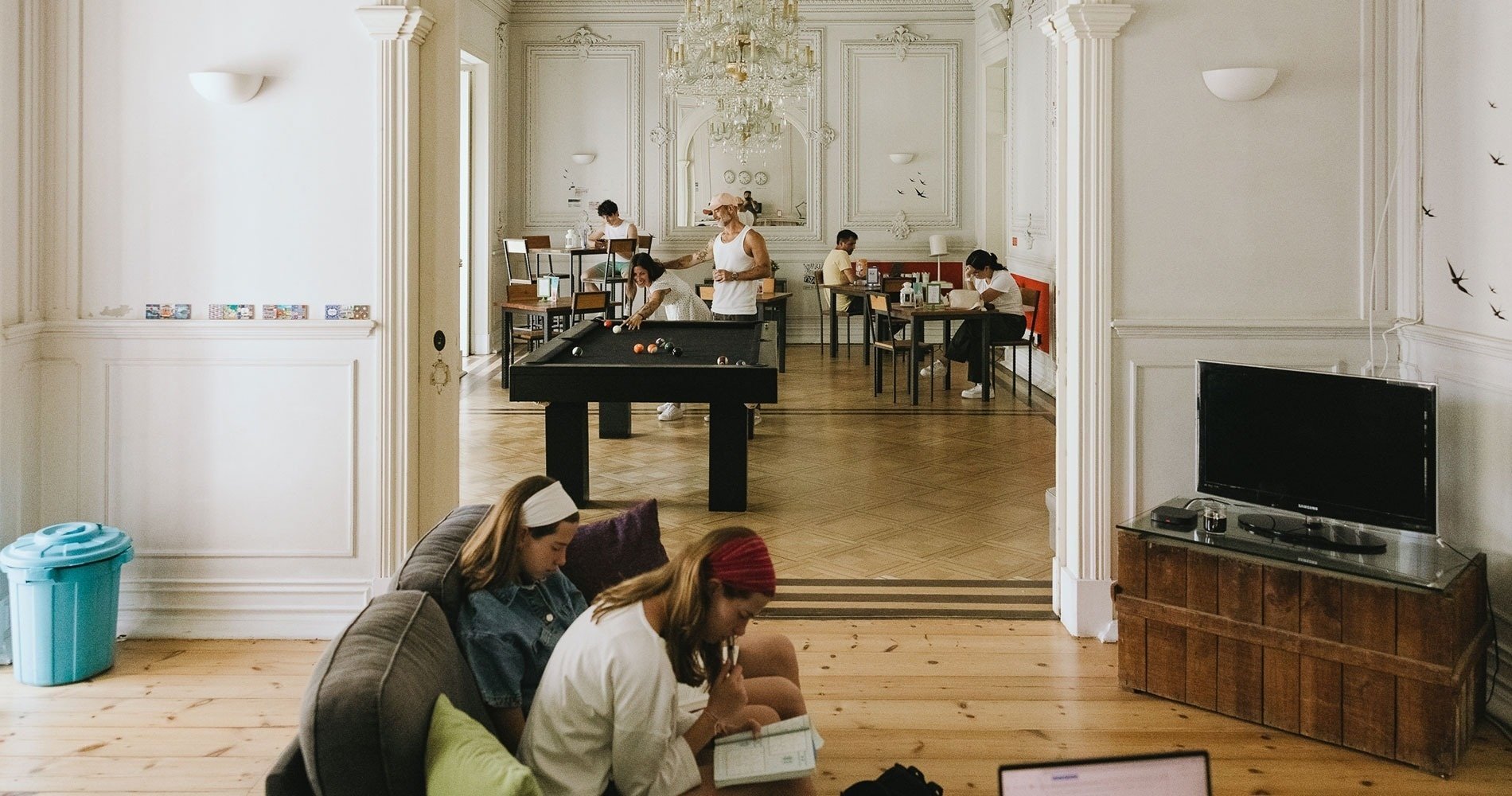dos mujeres se sientan en un sofá en una habitación con una mesa de billar