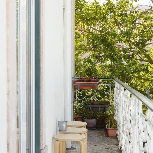 a balcony with wooden stools and potted plants
