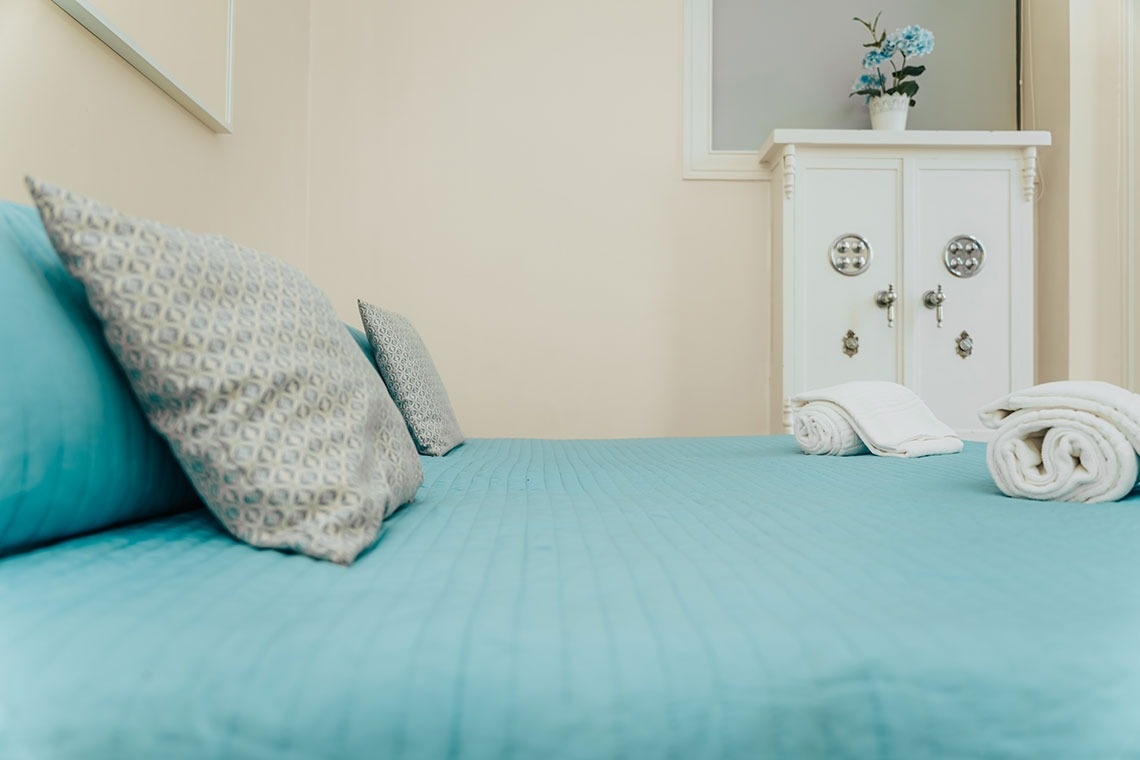 a bed with blue sheets and pillows in a bedroom