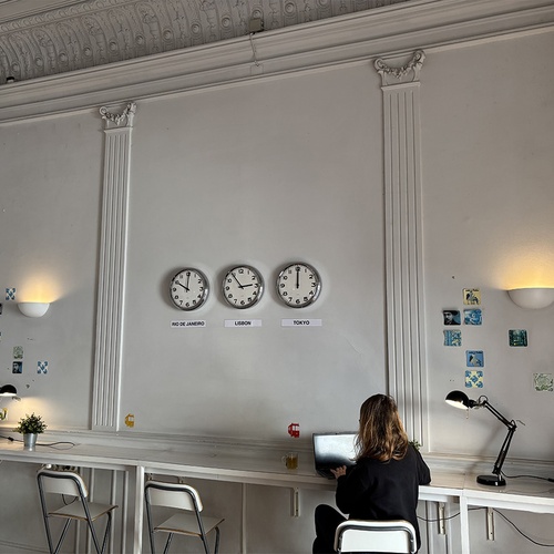 Área de co-working elegante em hotel, com fusos horários e laptop, ideal para trabalho remoto.