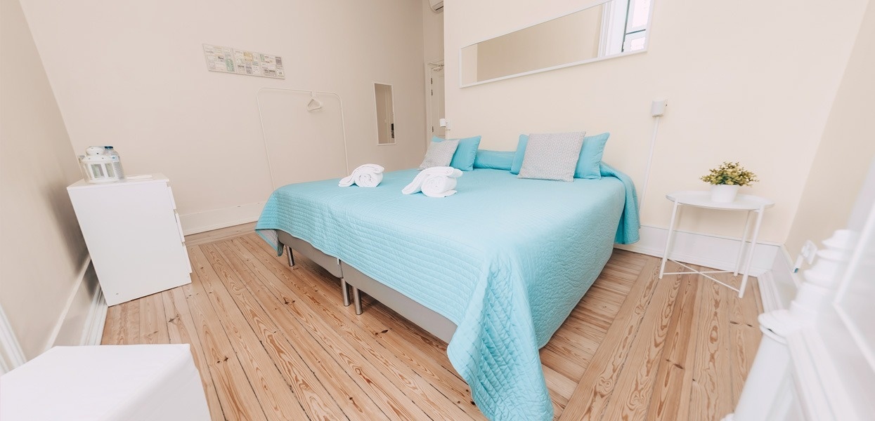 una habitación con una cama azul y una mesita blanca