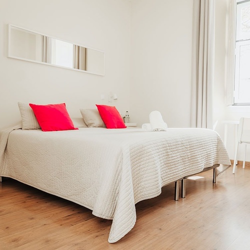 a bedroom with a white bed and red pillows
