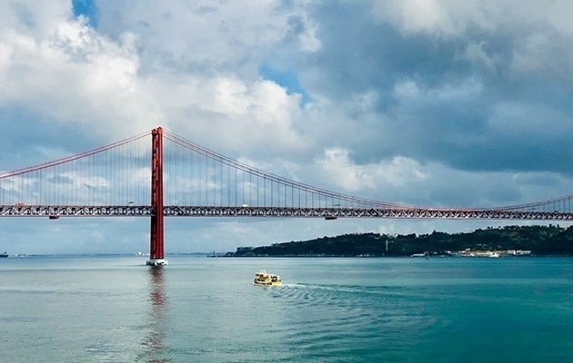 a yellow boat is going under a red bridge