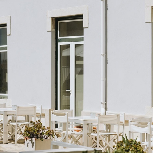 a white building with tables and chairs in front of it