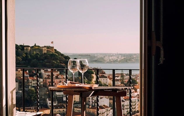 two wine glasses on a table with a view of a city
