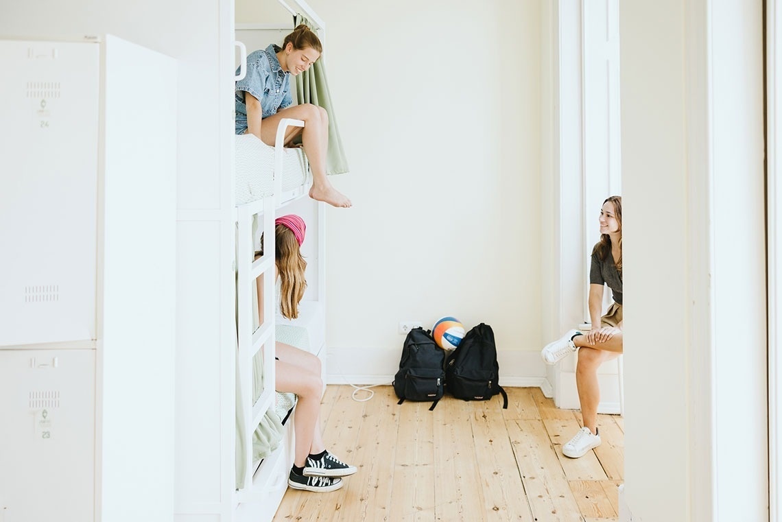 a girl sitting on a bunk bed talking to another girl