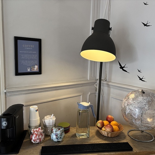 Cantinho de café acolhedor em hotel: máquina, frutas e água, ideal para hóspedes.