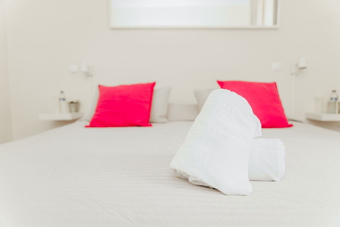 a bed with pink pillows and white towels on it