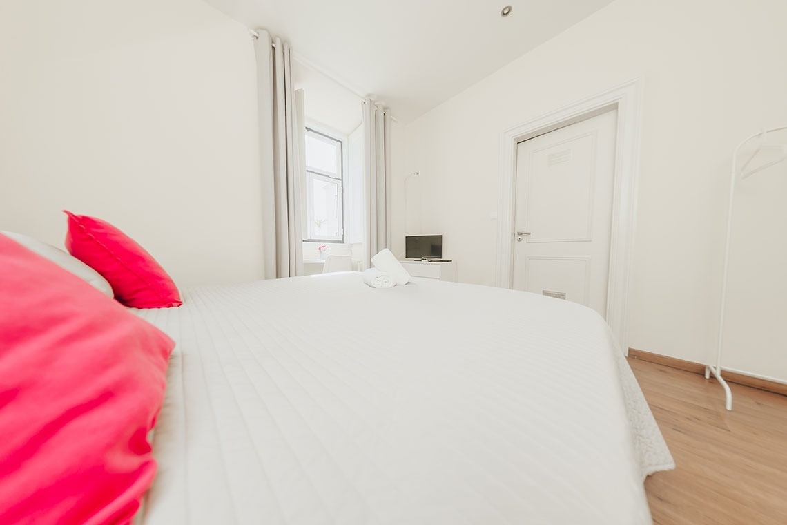 a bedroom with a white bed and a pink pillow