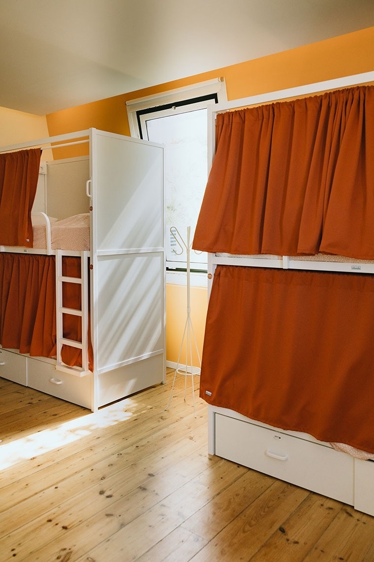 a bunk bed with orange curtains and a ladder