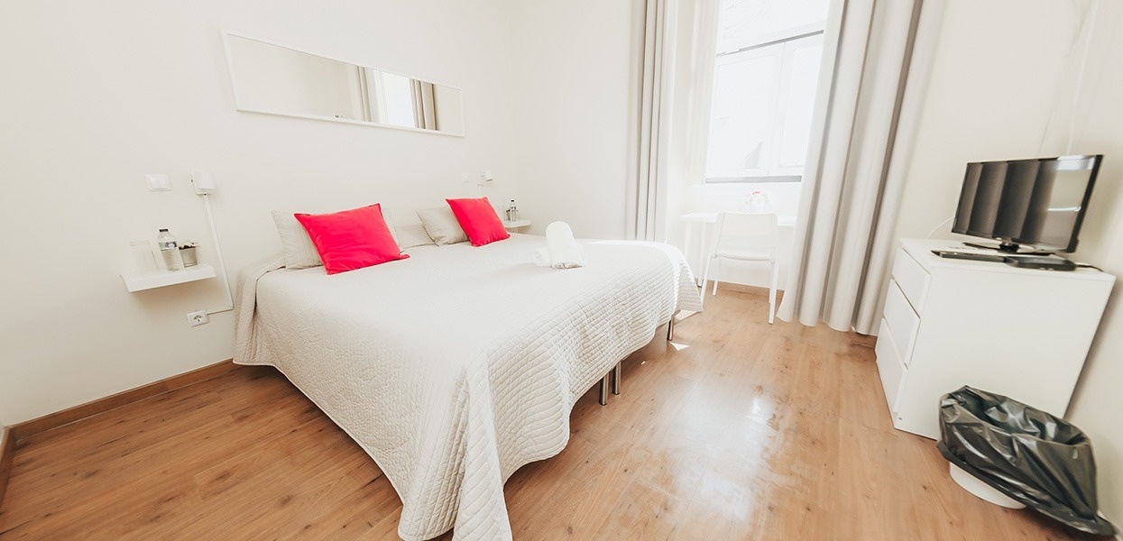 una habitación blanca con una cama y una televisión