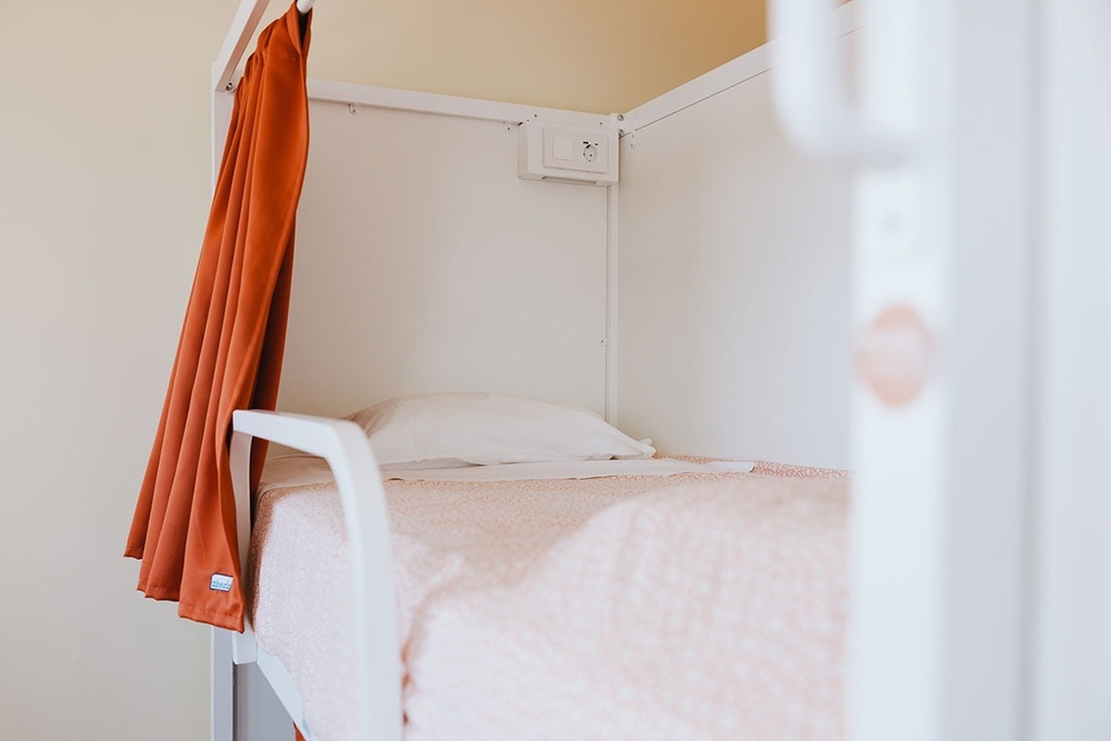 uma cama de beliche branca com uma cortina laranja