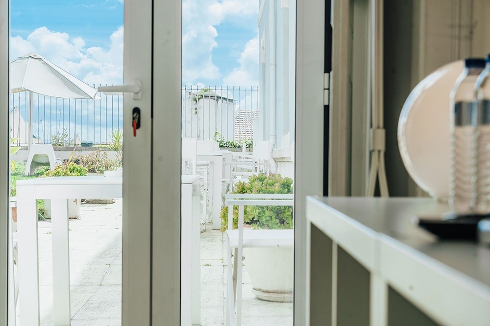 uma porta de vidro abre para uma varanda com mesas e cadeiras