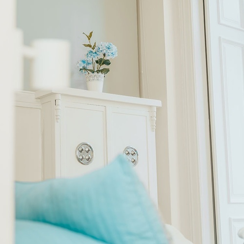 a vase of blue flowers sits on top of a white cabinet