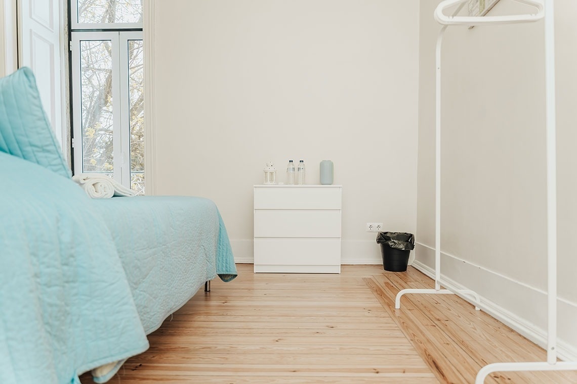 a bedroom with a blue blanket and a white dresser