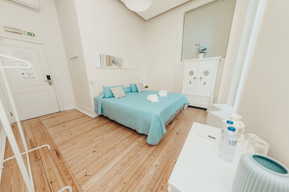 um quarto com uma cama azul e uma mesa branca